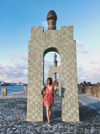 Woman standing against gate in city