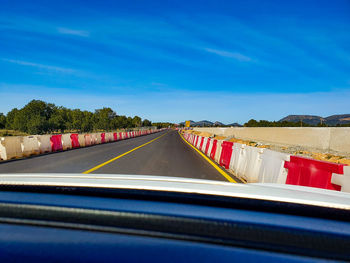 Road against blue sky seen through car windshield