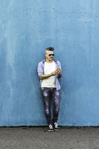 Full length portrait of young man standing against wall