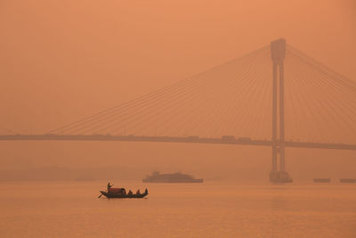 Scenic view of suspension bridge over sea against sky during sunset