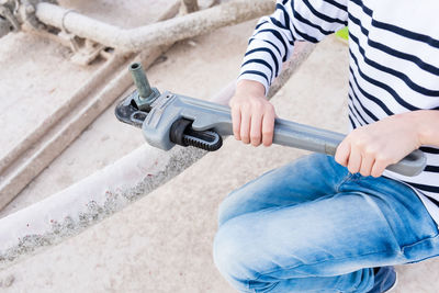 Midsection of woman holding wrench on metal