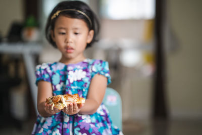 Little girl holding pizza indoor at home.
