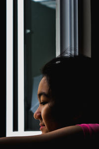 Close-up portrait of a young girl looking out the window