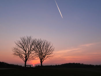 Silhouette bare tree on field against romantic sky at sunset