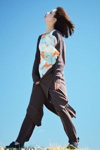 Low angle view of woman against clear blue sky