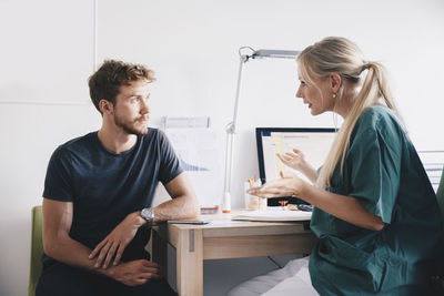 Female nurse explaining to young male patient at office in hospital