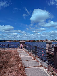 Footpath by sea against blue sky