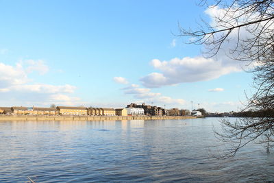 Scenic view of river by buildings against sky