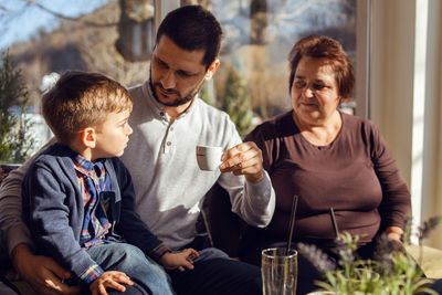 Father looking at son while sitting with mother at home