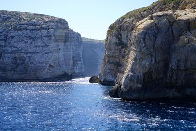 Rock formations by sea against clear sky