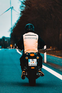 Rear view of man riding motorcycle on road