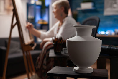 Gray vase on table woman in background