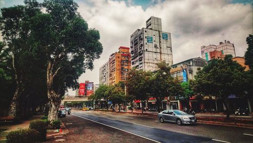 Cars on street by buildings against sky