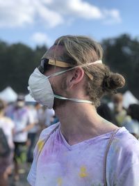 Young man wearing sunglasses and mask standing at music festival