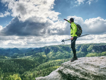 Slim body trek runner with backpack and trekking poles walk mountain trail. rocky part of path 