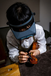 Young chinese violin maker at work in her workshop