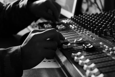 Cropped hands of man adjusting sound mixer knobs 