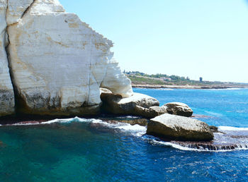 Rocks in sea against clear sky