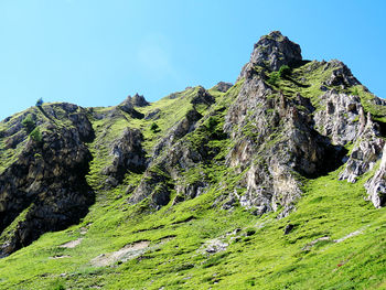 Low angle view of green mountain against blue sky