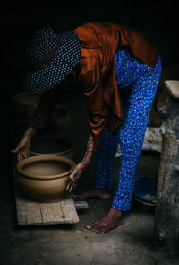 Side view of woman picking container at home