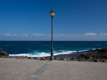 Street light on beach against sky