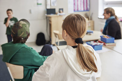 Rear view of girl sitting in classroom