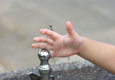 Cropped hand of child by drinking fountain