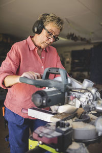 Senior woman using circular saw at workshop