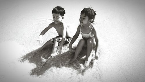 High angle view of children sitting on shore at beach