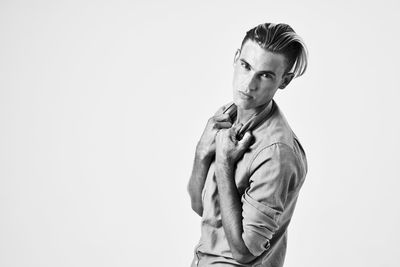 Portrait of young man standing against white background