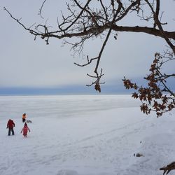 People on snow covered land against sky