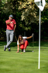 Couple playing golf, young woman reading green, getting ready to putt