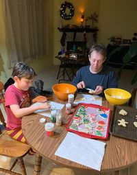 Father and son making food while sitting by table