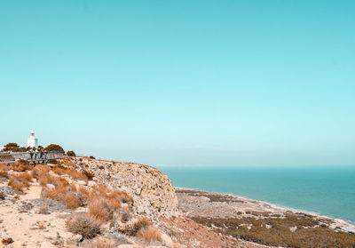 Scenic view of sea against clear sky with lighthouse on cliff