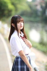 Young woman looking away while sitting outdoors