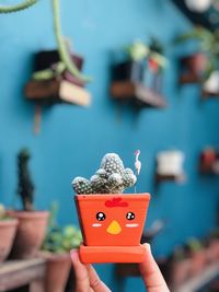 Close-up of hand holding small toy in potted plant