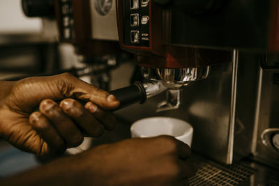 Cropped hand of male owner making coffee in cafe