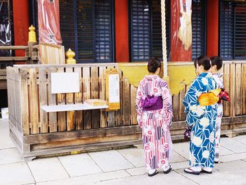 Full length of women wearing traditional clothing while standing outside temple