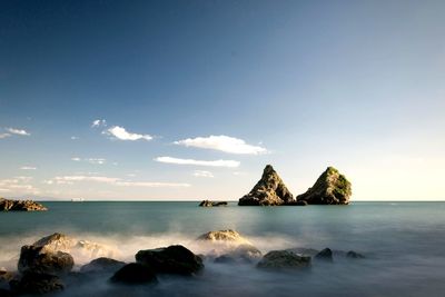 Scenic view of rocks in sea against sky