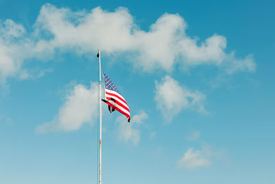 National flag of the united states of america waving over the blue sky with a little clouds