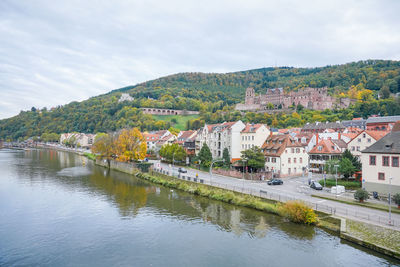 Town by river and buildings in city against sky