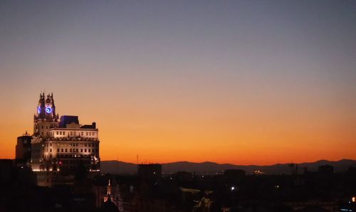 Illuminated cityscape against clear sky during sunset