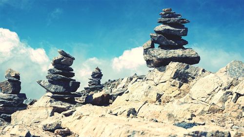 Stack of stones on rock against sky