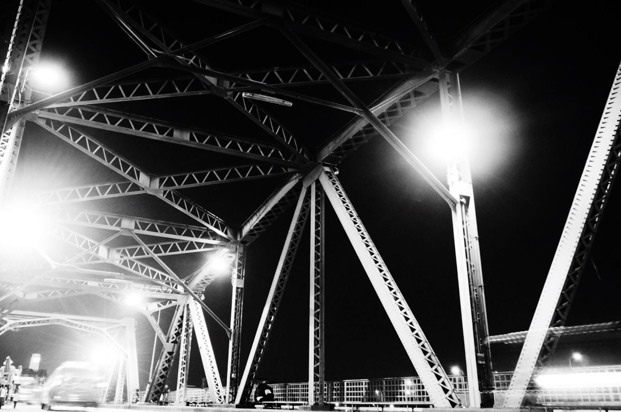 illuminated, low angle view, built structure, night, architecture, connection, engineering, bridge - man made structure, lighting equipment, metal, transportation, sky, travel destinations, no people, outdoors, travel, city, modern, light - natural phenomenon, diminishing perspective