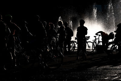 Silhouette people on bicycle at night