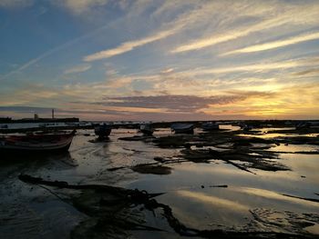 Boats moored in sea against sky during sunset