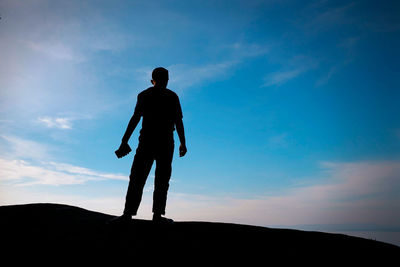 Low angle view of silhouette man standing against sky during sunset