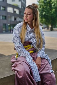 Beautiful young woman looking away while sitting outdoors