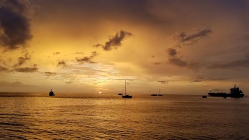 Silhouette boats sailing in sea against sky during sunset