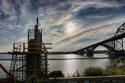 Bridge over river against cloudy sky